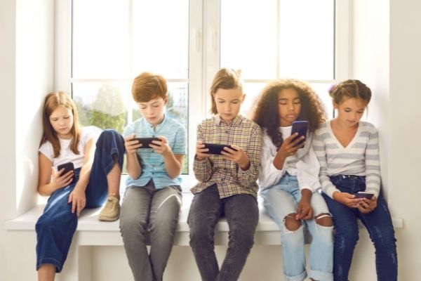 five kids on smart phones; distracted kids on mobile phones